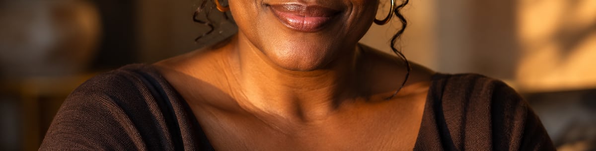Smiling woman in warm golden light, wearing gold hoop earrings